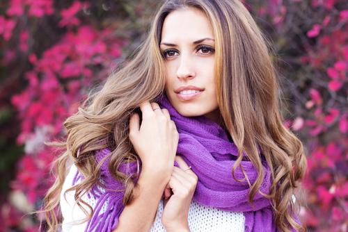 Woman in a scarf in front of purple flowers