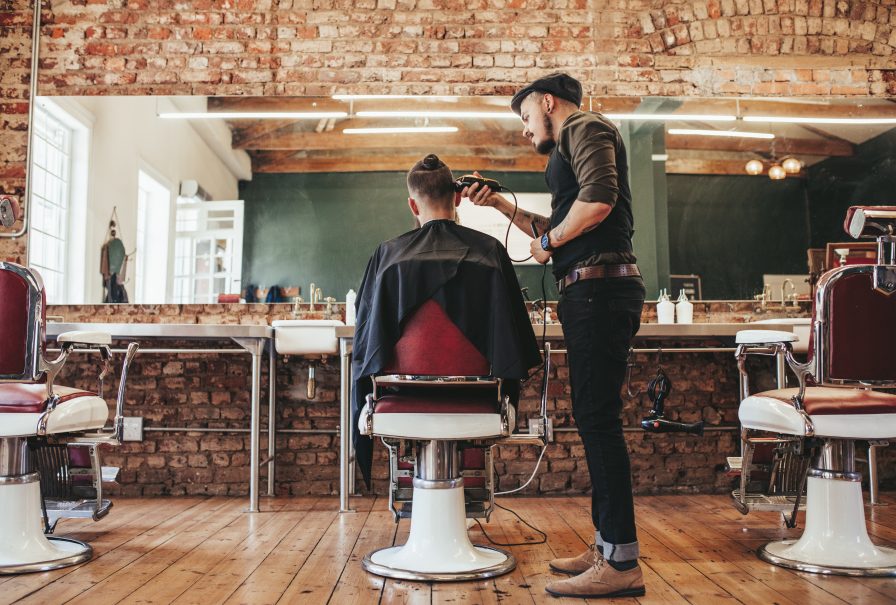 Two men cutting each others hair in a barber shop