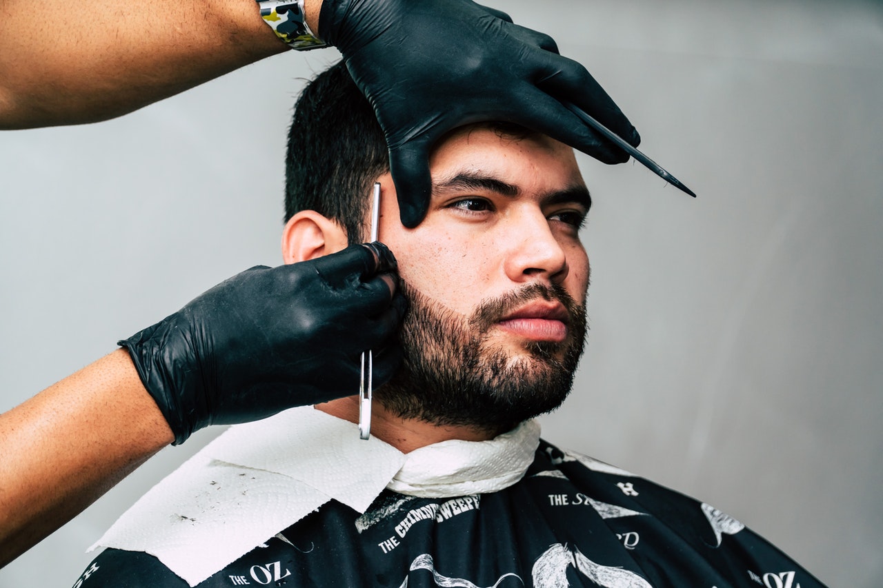 barber giving a handsome man a straight razor shave