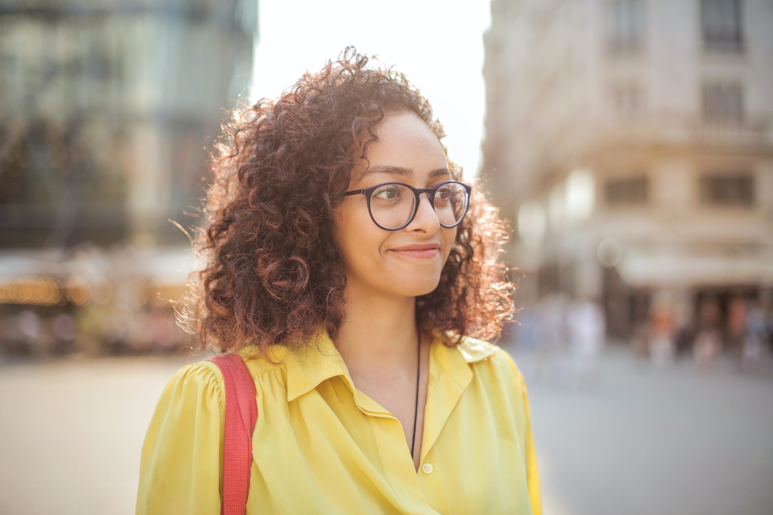 woman in a yellow top standing outside in a downtown area