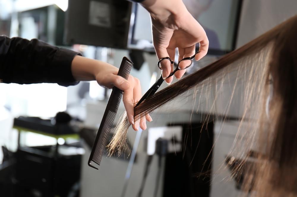 woman trimming another woman's hair in a salon